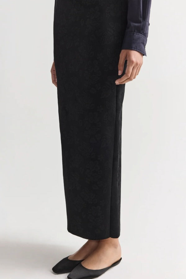 Side view of black lawton skirt on model wearing navy top and flats, against a white background.