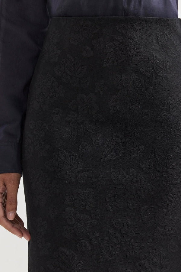 Front closeup view of black lawton skirt on model wearing navy top, against a white background.