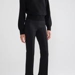 Front view of black lofty lara sweater on model wearing black pants and sandals, against a white background.