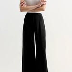 Front view of black slinky gene pant on model wearing white top and flats, against a white background.