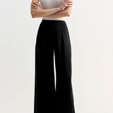 Front view of black slinky gene pant on model wearing white top and flats, against a white background.
