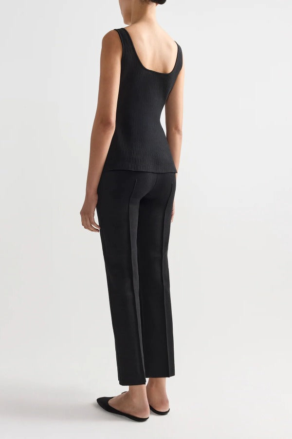 Back view of black combo windowpane inna top on model wearing black pants and flats, against a white background.