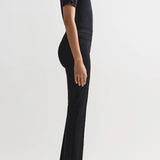 Side view of black combo windowpane louis pants on model wearing black t-shirt and flats, against a white background.