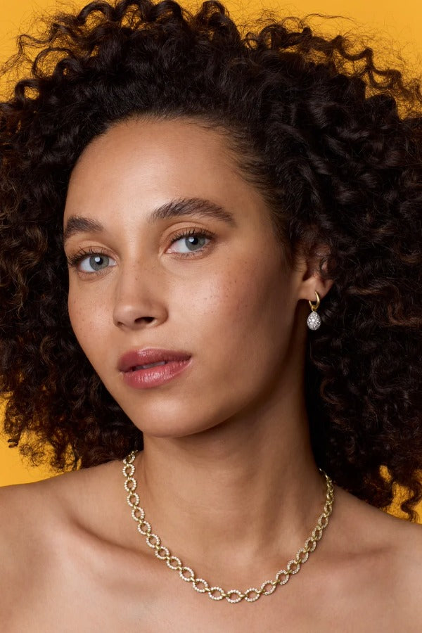 Front view of 18K WG YG Earrings on model, against an orange background.