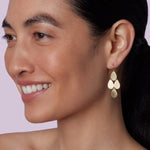 Front view of flat gold 18K YG 4 Drop Earrings on model, against a pink background.
