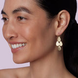 Front view of flat gold 18K YG 4 Drop Earrings on model, against a pink background.