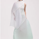 Front view of white silk wool pleats stole on model wearing light green dress and white clogs, against a white background.