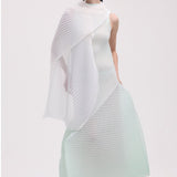 Front view of white silk wool pleats stole on model wearing light green dress and white clogs, against a white background.