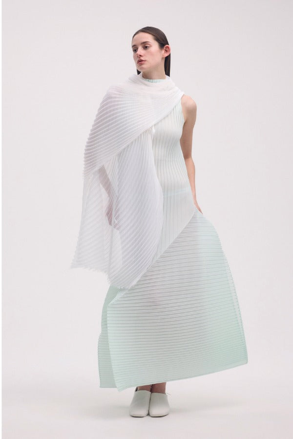 Front view of white silk wool pleats stole on model wearing light green dress and white clogs, against a white background.