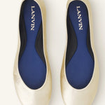 Overhead view of gold ballerina flats on white background, with no model shown.