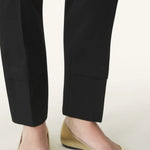 Front and side view of gold ballerina flats on model wearing black pants, against a white background.