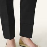 Front and side view of gold ballerina flats on model wearing black pants, against a white background.