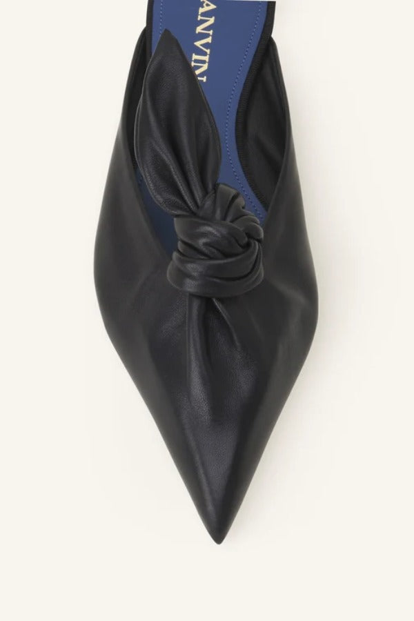 Overhead closeup of black flat mule bow on white background, with no model shown.