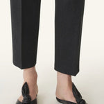 Front and side view of black flat mule bow on model wearing black pants, against a white background.