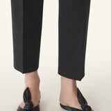 Front and side view of black flat mule bow on model wearing black pants, against a white background.