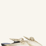 Pair View of gold flat mule bow on white background, with no model shown.