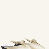 Pair View of gold flat mule bow on white background, with no model shown.