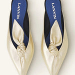 Overhead view of gold flat mule bow on white background, with no model shown.