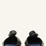 Back view of black flat mule bow on white background, with no model shown.