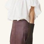 Side view of cloth puffy sleeves top on model wearing burgundy skirt, against a white background.