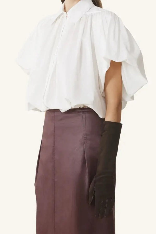 Side view of cloth puffy sleeves top on model wearing burgundy skirt, against a white background.