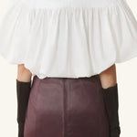 Back view of cloth puffy sleeves top on model wearing burgundy skirt, against a  white background.