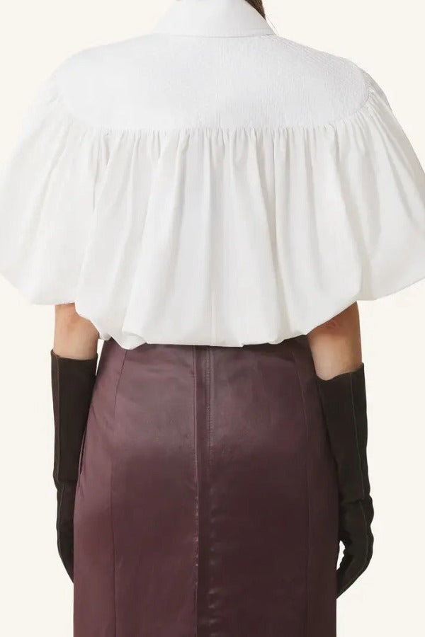 Back view of cloth puffy sleeves top on model wearing burgundy skirt, against a  white background.