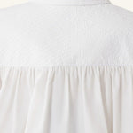 Back closeup view of cloth puffy sleeves trop on model, against a white background.