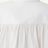 Back closeup view of cloth puffy sleeves trop on model, against a white background.
