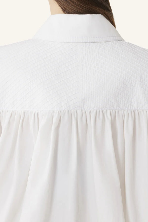 Back closeup view of cloth puffy sleeves trop on model, against a white background.