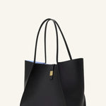 Side view of black tote bag on white background, with no model shown.