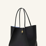 Side view of black tote bag on white background, with no model shown.