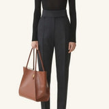 Front view of black turtleneck jumper on model wearing grey pants and flats, against a white background.