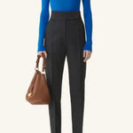 Front view of electric blue turtleneck jumper on model wearing grey pants, against a white background.