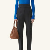 Front view of electric blue turtleneck jumper on model wearing grey pants, against a white background.