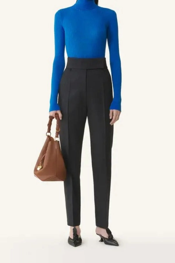 Front view of electric blue turtleneck jumper on model wearing grey pants, against a white background.