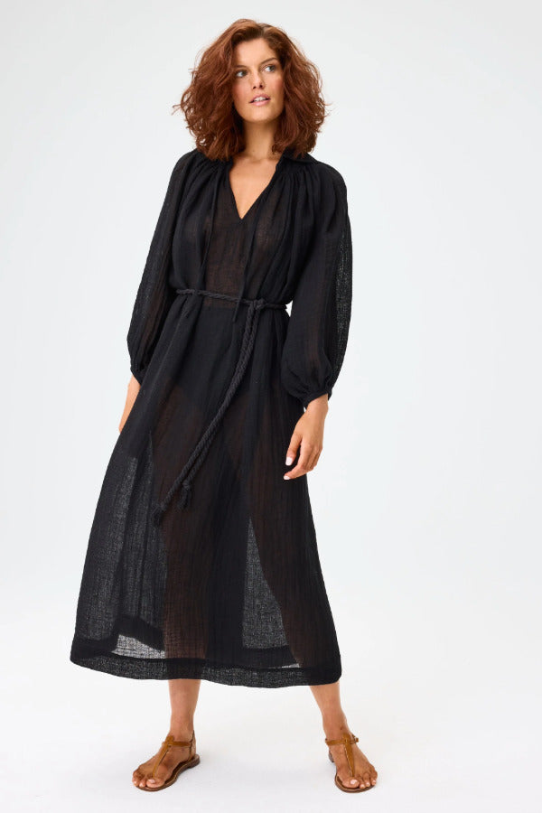 Front view of black maxi poet dress on brown-haired model wearing brown sandals, against a white background.