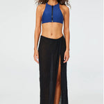 Front view of black sarong skirt on model wearing blue zipper bathing suit top and silver sandals, against a white background.