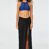 Front view of black sarong skirt on model wearing blue zipper bathing suit top and silver sandals, against a white background.