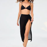 Front view of black sarong skirt on model wearing black bikini top and silver sandals, against a white background.