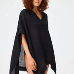 Front view of black short beach poncho on brown-haired model wearing black swim suit, against a white background.