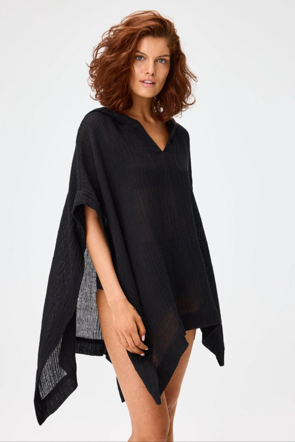 Front view of black short beach poncho on brown-haired model wearing black swim suit, against a white background.