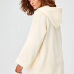 Side view of cream terry beach tunic on brown-haired model, against a white background.