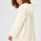 Side view of cream terry beach tunic on brown-haired model, against a white background.