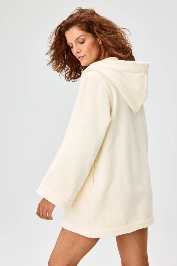 Side view of cream terry beach tunic on brown-haired model, against a white background.
