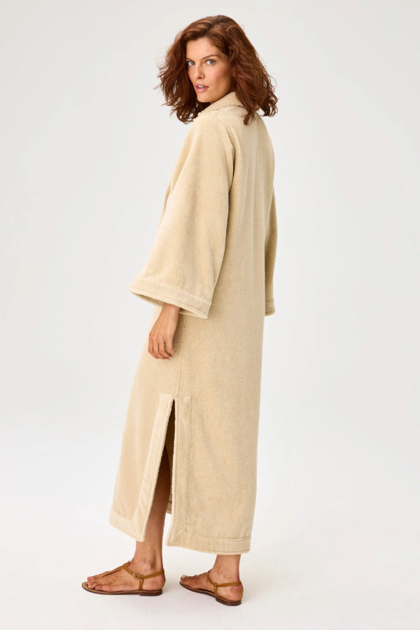 Back view of sand terry tunic caftan on model wearing brown sandals, against a white background.