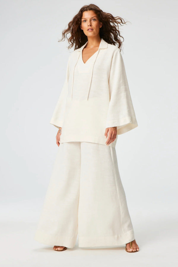 Front view of white low waist wide leg pant on brown-haired model wearing white top and brown sandals, against a white background.