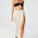 Front view of white sarong skirt on brown-haired model wearing black swim suit and silver sandals, against a white background.