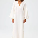 Front view of white tunic caftan on brown-haired model wearing silver sandals, against a white background.