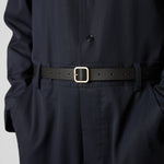 Front view of black marsell quadra belt on model wearing black shirt and trousers, against a white background.